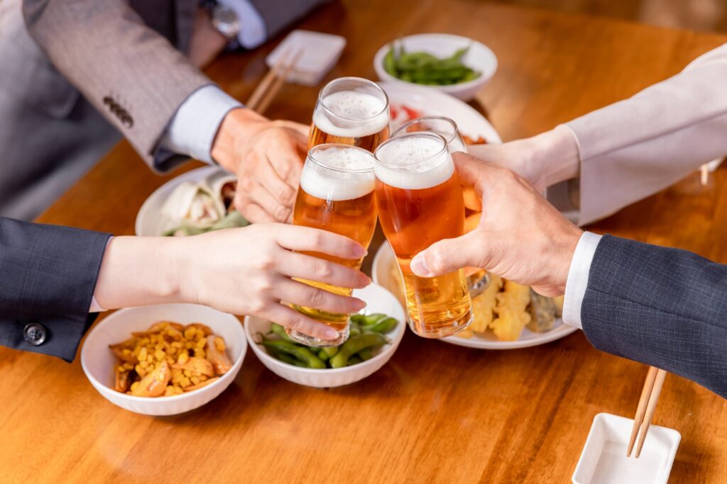 賑やかな居酒屋の店内で、お客様がジョッキを合わせて乾杯している様子。居酒屋バイト経験者が語る、接客の忙しさや店内の活気に関する口コミセクションのイメージ写真。