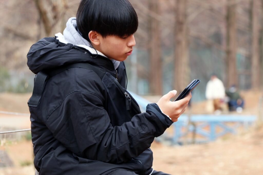 バイトを辞めることを電話で伝えるのはアリか？言い方やマナーを解説。スマホを見ている男性。