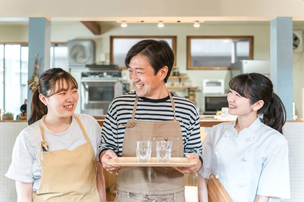 カフェのバイト面接で聞かれる質問、志望動機、服装マナーをチェック。カフェで店員がチームワーク良く働いている様子。