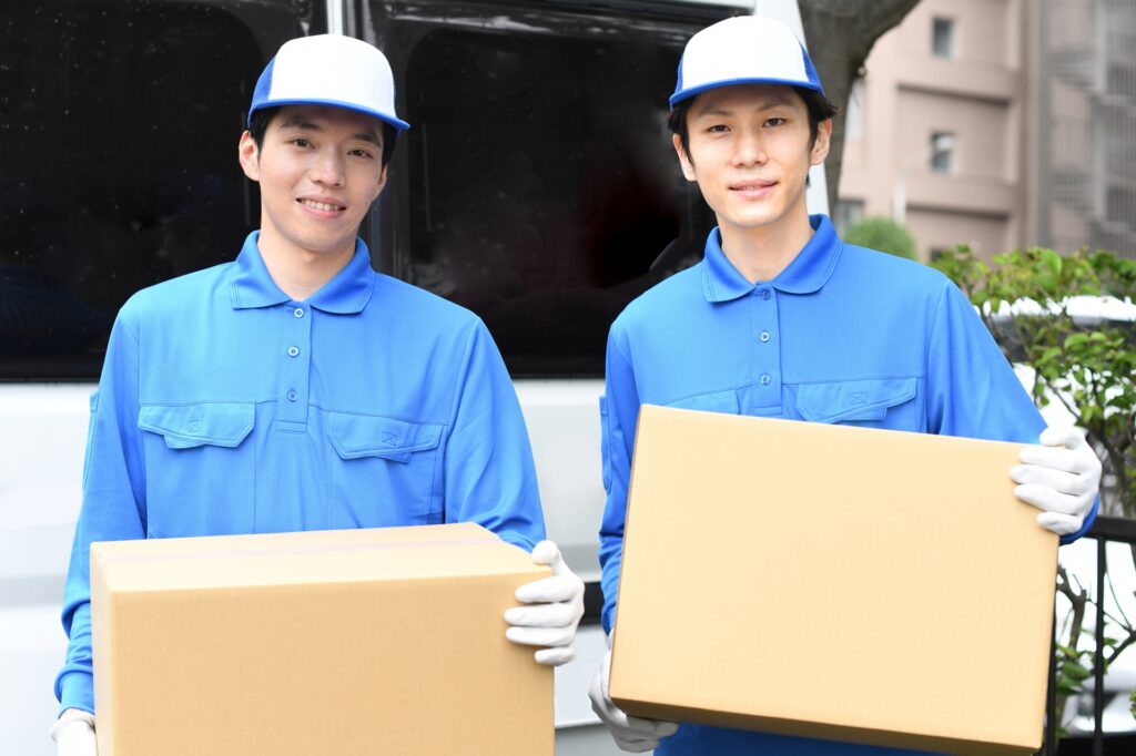 引越しバイトの面接・志望動機記事のアイキャッチ。協力して段ボールを運ぶ若いスタッフ2人の様子。