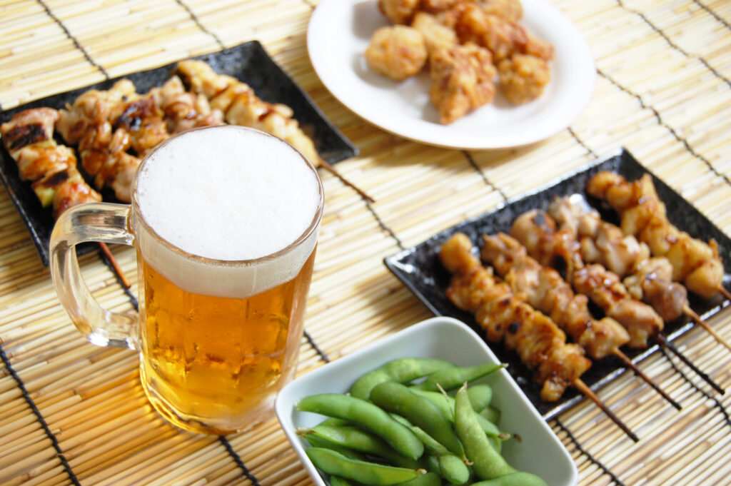 居酒屋のテーブルに並んだ冷えたビールと美味しそうなおつまみ。居酒屋バイトの「きつい」という現実や「辞めたい」時の対処法を振り返り、自分に合った働き方を考えるためのまとめセクションのイメージ写真。